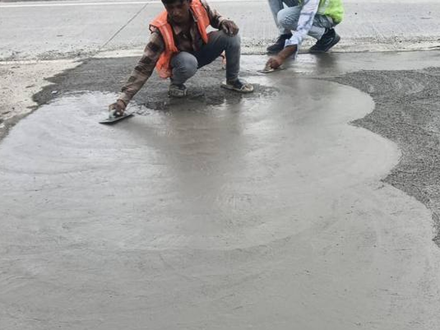 Workers finishing a freshly poured concrete surface